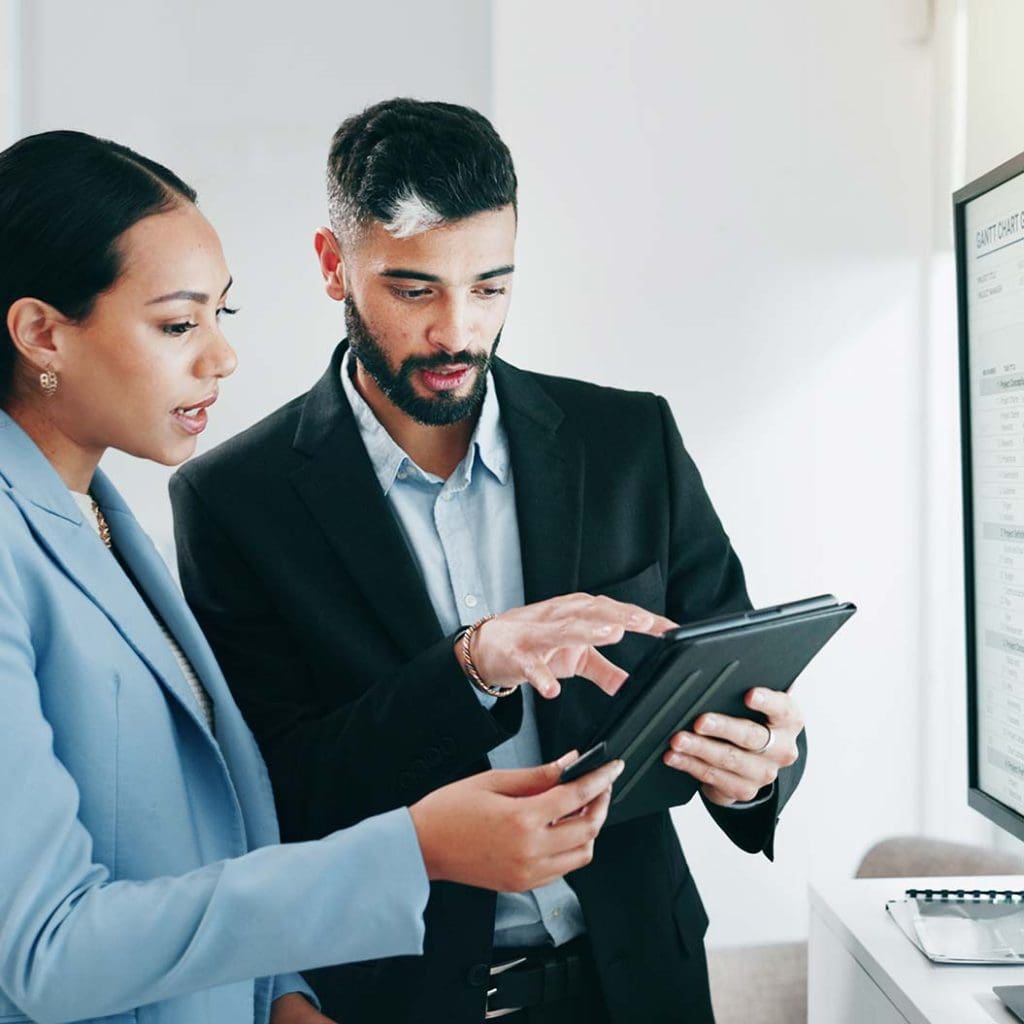 Business people reading tablet and talking together in office environment.